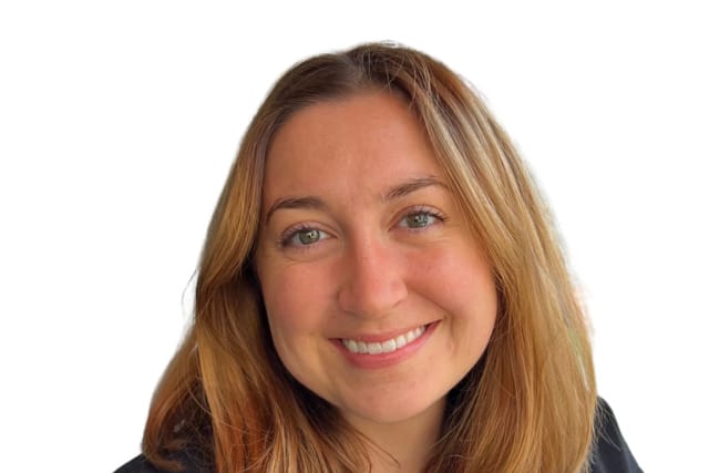 Smiling person with medium-length brown hair wearing a black top against a white background.