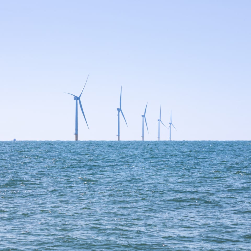 Offshore wind turbines in the sea under a clear blue sky