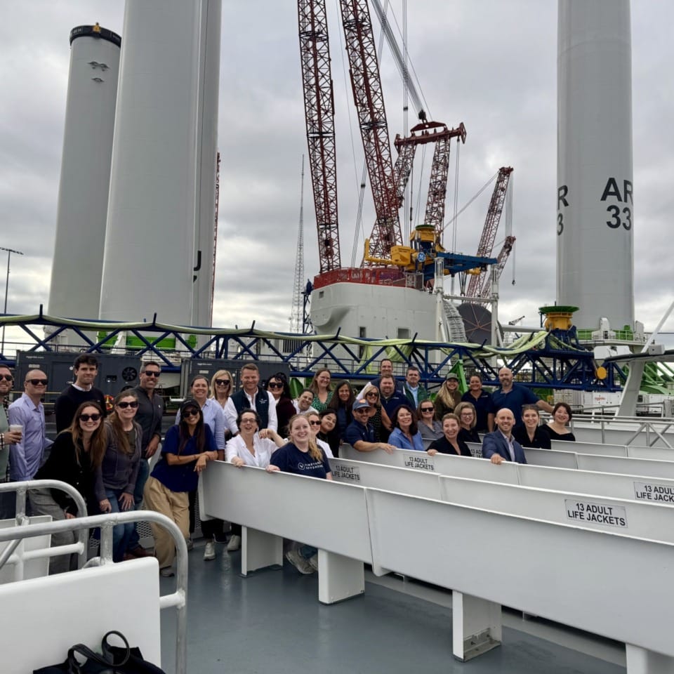 Group of people on a boat tour with cranes and industrial equipment in the background.